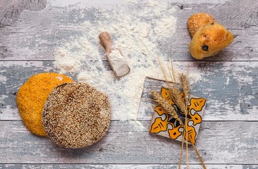 Assorted fresh breads on an old wooden table with flour and a napkin