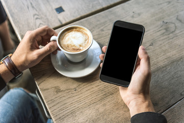cropped shot of man with cup of cappuccino using smartphone with blank screen