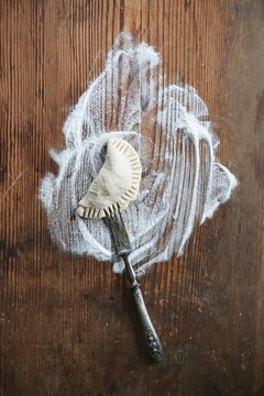 Overhead view of maultasche on old wooden board with flour and fork