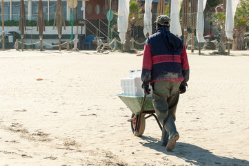 worker walking on the sand with a wheelbarrow