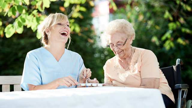 Pflegerin und Seniorin im Garten