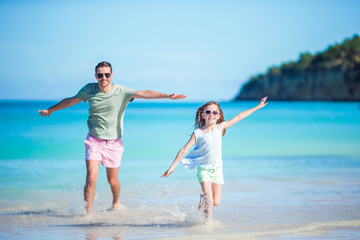 Family at tropical beach walking together on tropical Carlisle bay beach with white sand and turquoise ocean water at Antigua island in Caribbean.