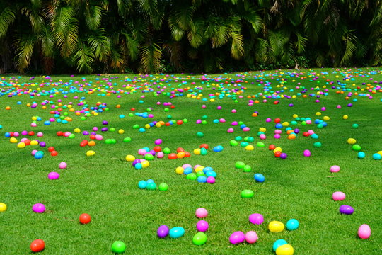 An Easter Egg Hunt With Colorful Plastic Eggs On A Green Lawn