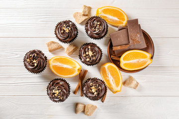 Delicious chocolate cupcakes with orange on wooden table