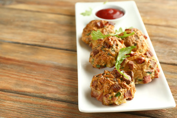 Plate with tasty sausage balls on wooden table