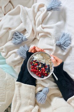 Overhead view of woman holding bowl of porridge and fruits