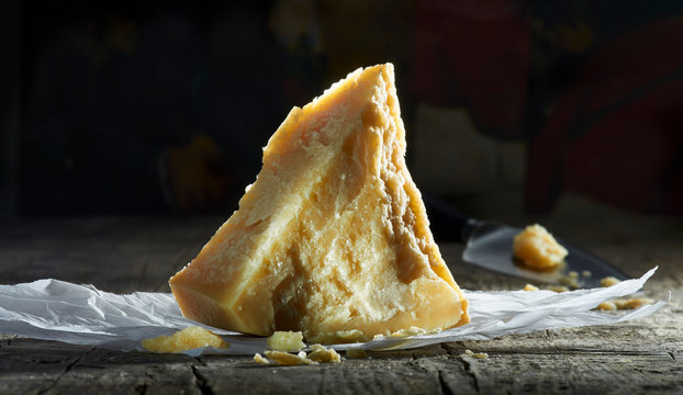 A piece of parmesan on paper next to a parmesan knife