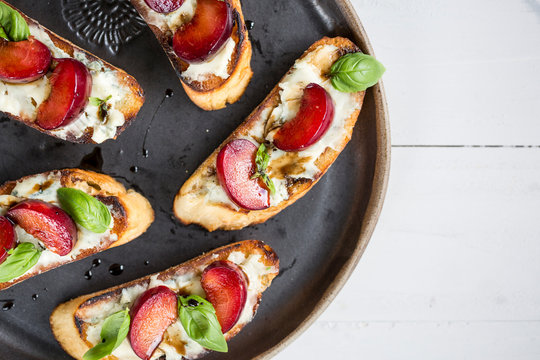 Overhead view of crostini with plum and basil