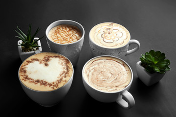 Cups with tasty aromatic coffee on black background