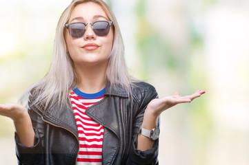 Young blonde woman wearing fashion jacket and sunglasses over isolated background clueless and...