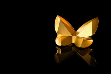 Golden statuette of butterfly on black background
