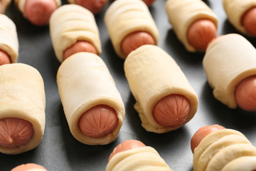 Tasty sausage rolls on baking dish, closeup