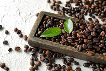 Board with roasted coffee beans on white table