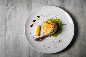 top view on baked trout with stuffing, salad, lemon and sauce