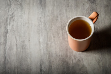 peach-colored cup of tea stands on gray background