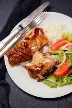 roasted pork with boiled rice and salad on white plate