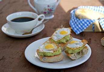 Healthy breakfast, toast with avocado mash and fried quail egg on a brown background.