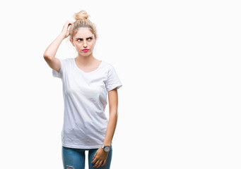 Young beautiful blonde woman wearing white t-shirt over isolated background confuse and wonder about question. Uncertain with doubt, thinking with hand on head. Pensive concept.