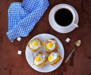 Healthy breakfast, toast with avocado mash and fried quail egg on a brown background.