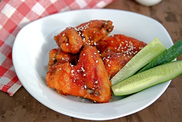 Baked chicken wings in a barbecue sauce, sprinkled with sesame. Served with sliced fresh cucumbers.