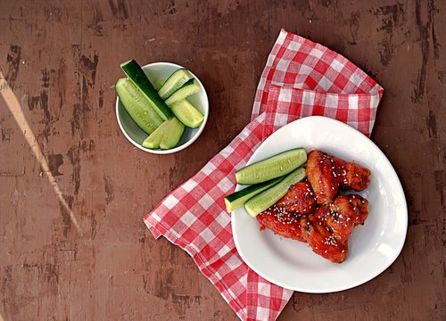 Baked chicken wings in a barbecue sauce, sprinkled with sesame. Served with sliced fresh cucumbers.