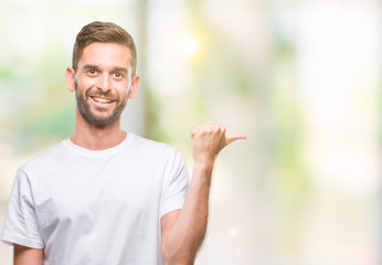 Young handsome man over isolated background smiling with happy face looking and pointing to the side with thumb up.