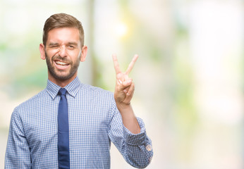 Young handsome business man over isolated background smiling with happy face winking at the camera doing victory sign. Number two.