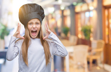 Young beautiful girl wearing chef hat uniform over isolated background crazy and mad shouting and yelling with aggressive expression and arms raised. Frustration concept.