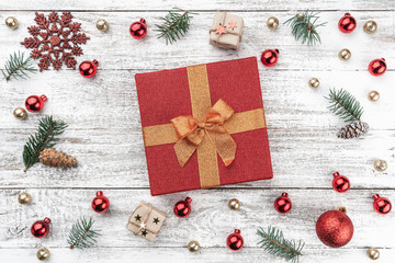 Frame on christmas background of old wood. Red and gold Baubles. Fir branches and cones. In the center a red gift. Xmas items. Top view.