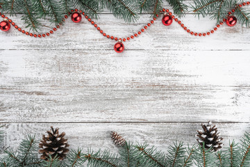 Xmas card. Old wooden Christmas background. Fir branches and cones. Red baubles and garlands. Top view. Space for your text.