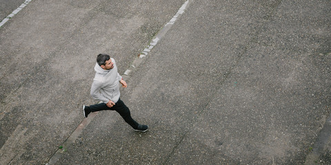 Top view of sporty man running in winter on urban asphalt. Male runner training outside.
