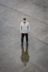 Urban sportsman taking a running and fitness workout rest. Sporty man resting after outdoor rainy winter training.