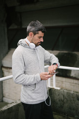 Urban runner using sporty smart watch and smartphone app for checking training goals. Contemporary sport and running concept.