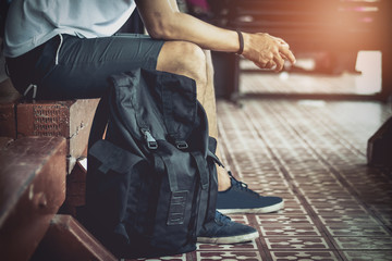 Tourist with backpack waiting for train at station in the evening with sunset.Image is mood tone..