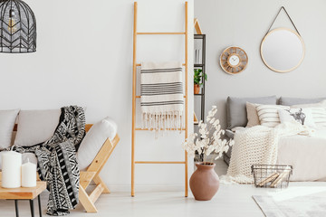 Wooden ladder with blanket between elegant settee with patterned blanket and comfortable bed with...