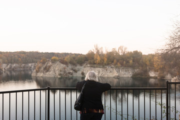 Starsza kobieta podziwia krajobraz. Jesień. Jezioro w tle 