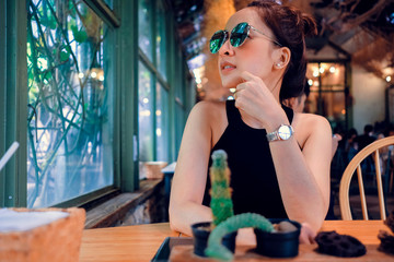 Portrait of stylish young asian woman wear sunglass sitting at cafe vintage style