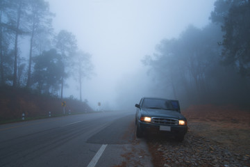 car beside the road with full of fog is bad weather.