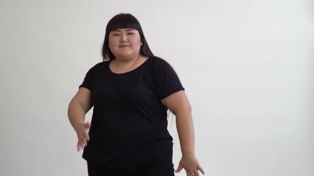 authentic fat Asian girl dancing and enjoying life on white background. Life outside of the stereotypes of today's youth. Concept idea