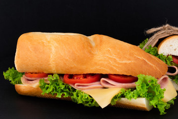 sandwich with with ham, cheese, tomatoes, lettuce on over stone