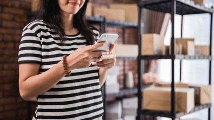 hand using smart phone and packages shelf in background