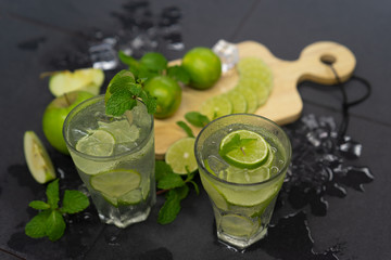 Mojito cocktail  fresh tropical beverage , lime juice, soda water and ice on black stone  table.