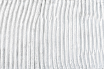 White plaster cement structure with relief curved strips. Background texture of vertical cement uneven wavy strips