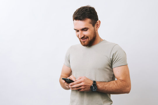 Happy young man using phone over white background and smiling