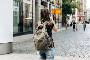 The girl on the street takes pictures of the beautiful buildings in Leipzig in Germany. She makes a...