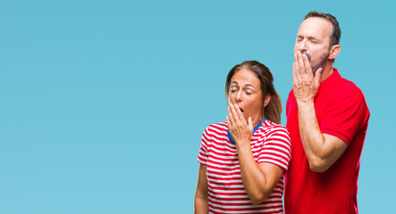 Middle age hispanic couple in love over isolated background bored yawning tired covering mouth with hand. Restless and sleepiness.