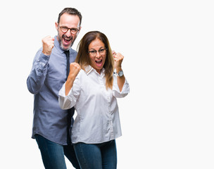 Middle age hispanic couple in love wearing glasses over isolated background very happy and excited doing winner gesture with arms raised, smiling and screaming for success. Celebration concept.