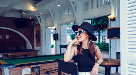 Fototapeta na wymiar posing smile relax by beautiful woman in holiday trip with wear hat and sun glasses with blur inside bar