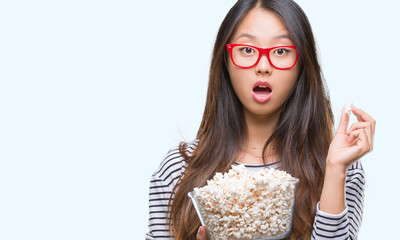 Obraz premium Young asian woman eating popcorn over isolated background scared in shock with a surprise face, afraid and excited with fear expression
