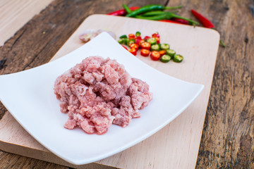 meat with vegetables and spices on wooden background